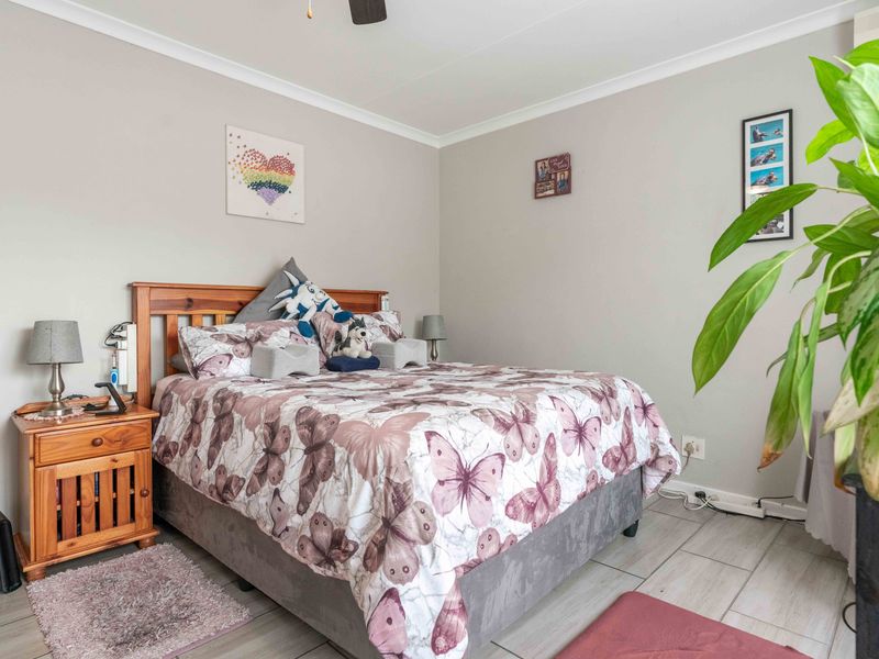 A well-maintained bedroom featuring neutral wall tones, tiled flooring, and a ceiling fan, providing a comfortable and functional living space.