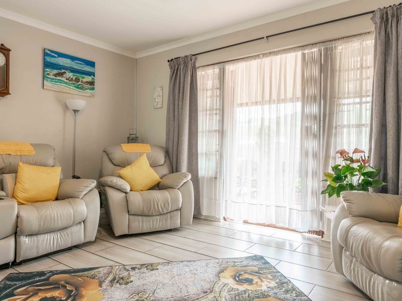 A bright and comfortable living room featuring neutral tiled flooring and a large sliding glass door that provides access to the outdoor area.