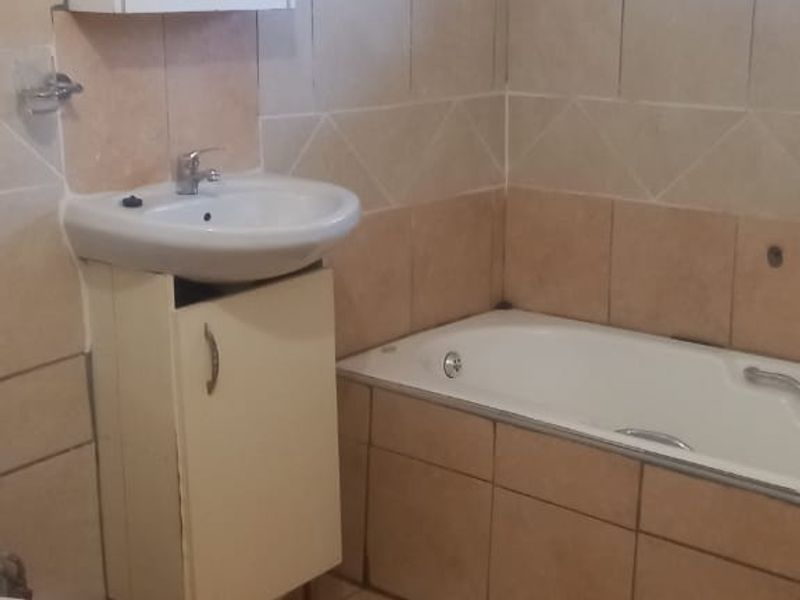 A functional bathroom featuring a bathtub, vanity with basin, and tiled finishes. The space is ready for a modern update to enhance its appeal.