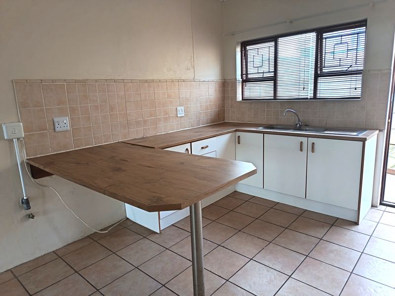 A functional kitchen featuring built-in cabinetry, laminate countertops, a breakfast bar, and tiled flooring, offering a clean and practical workspace.