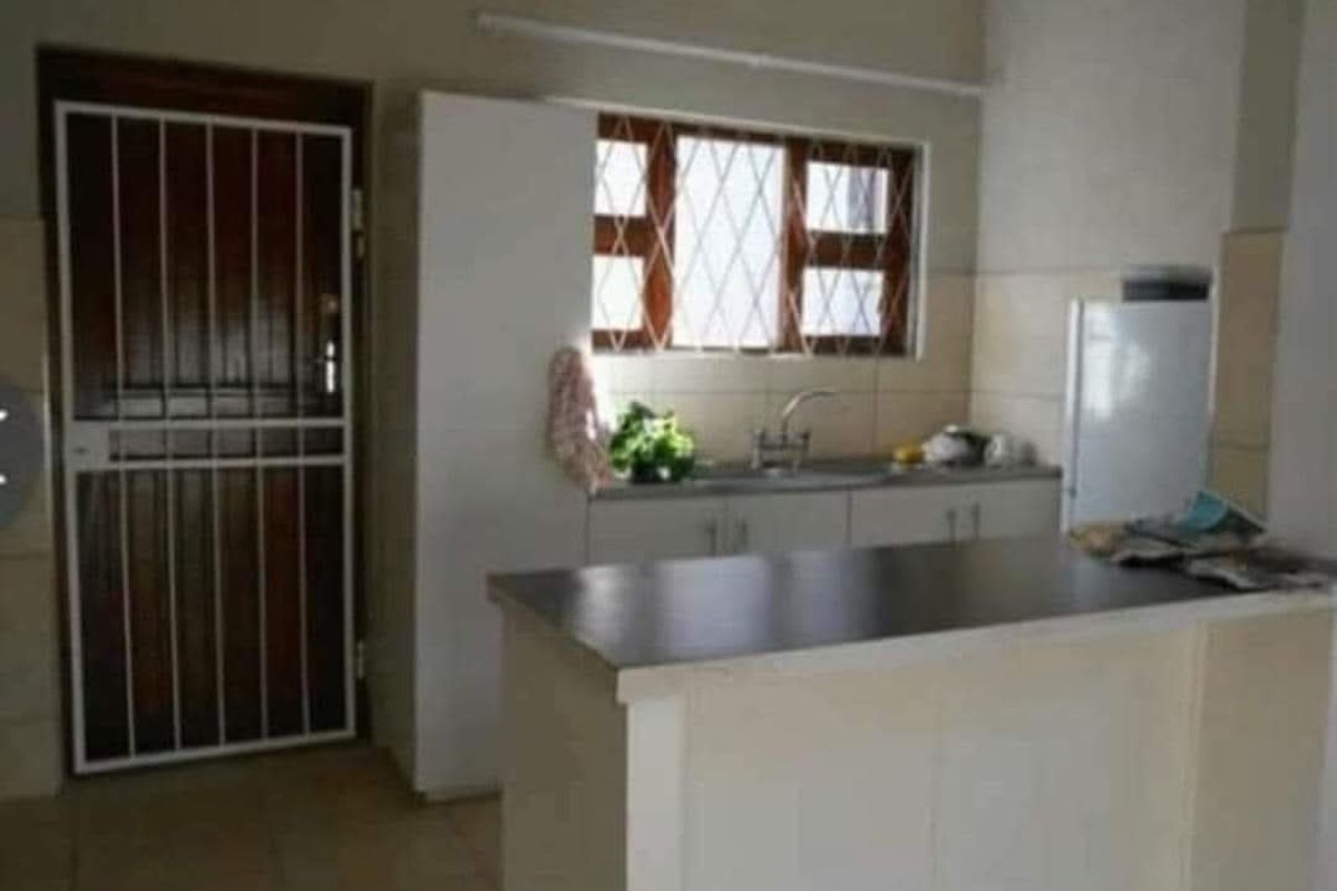A functional kitchen space featuring white cabinetry, a breakfast bar, and a security gate at the entrance.