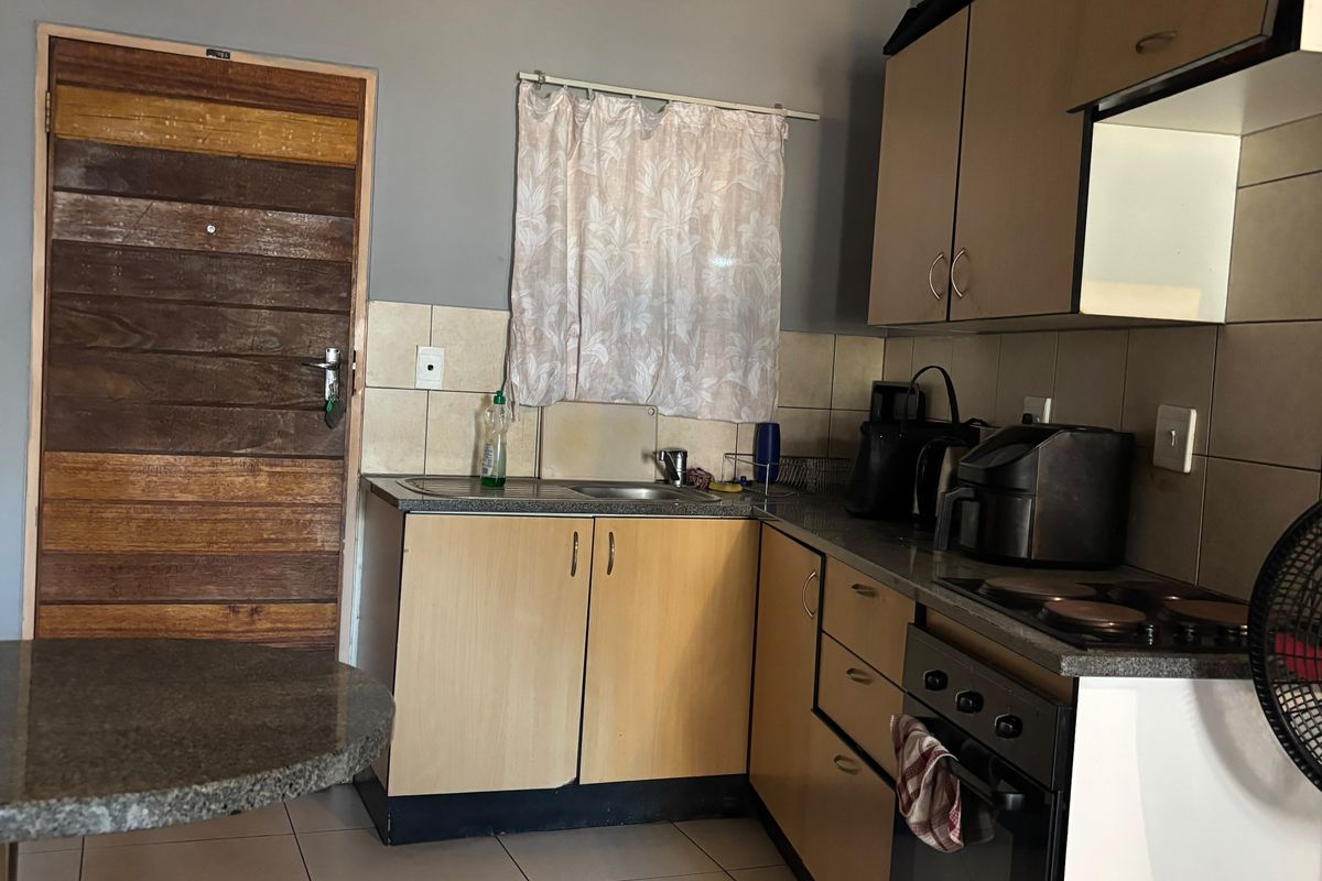 A functional kitchen featuring laminate cabinetry, built-in oven, electric hob, and tiled flooring, offering a practical layout for daily meal preparation.