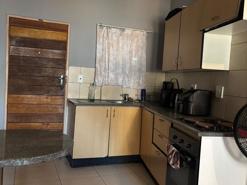 A functional kitchen featuring laminate cabinetry, built-in oven, electric hob, and tiled flooring, offering a practical layout for daily meal preparation.