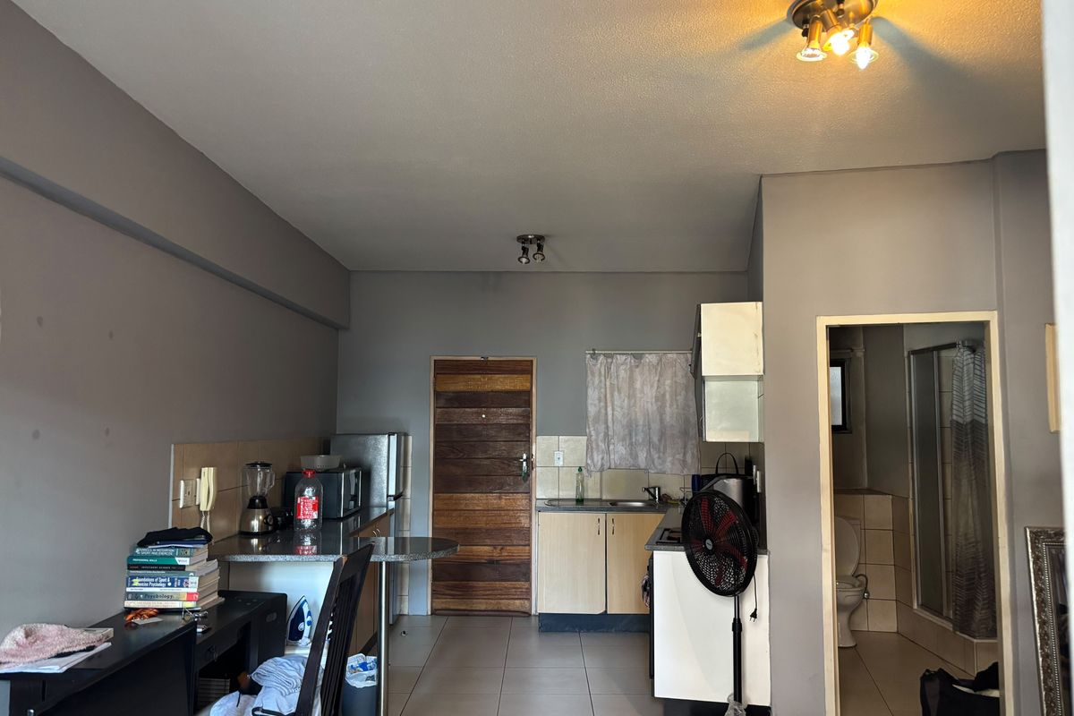 Open plan living area featuring a compact kitchen with built-in cabinetry, breakfast bar, and direct access to the bathroom.