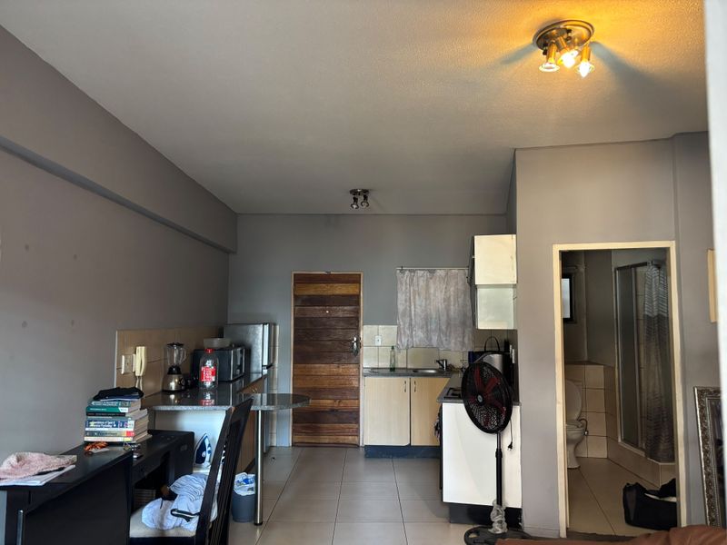 Open plan living area featuring a compact kitchen with built-in cabinetry, breakfast bar, and direct access to the bathroom.