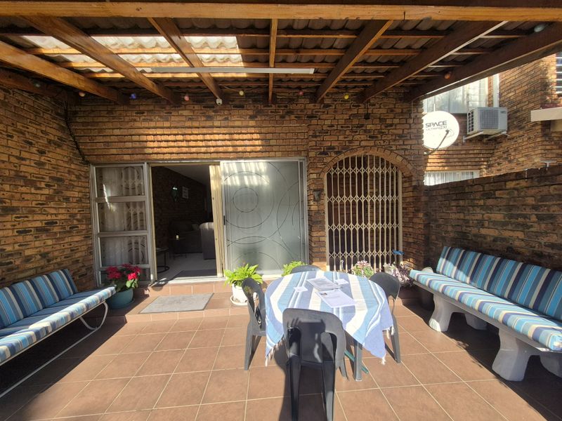 Covered patio area featuring exposed brick walls, tiled flooring, and a timber pergola, providing a functional outdoor entertainment space with direct access to the interior.