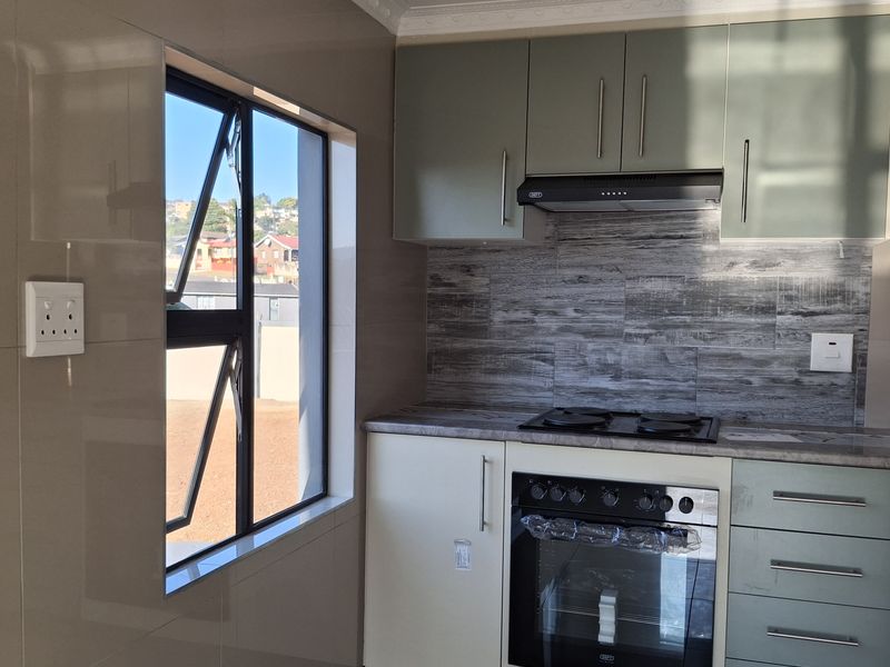 Modern kitchen featuring sleek built-in cabinetry, a fitted oven and hob, extractor fan, and contemporary tiled finishes.