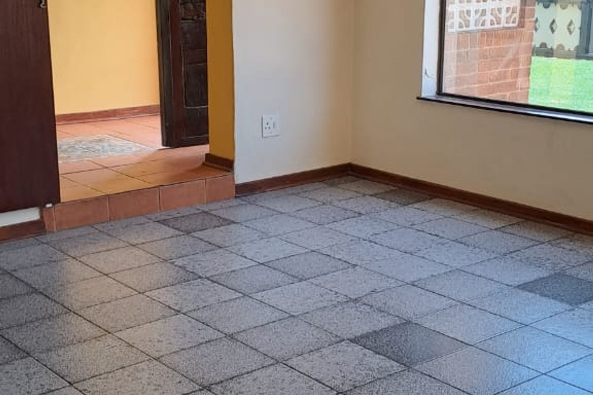 An empty living room featuring tiled flooring, a sliding door leading to an adjacent space, and a window with views of the exterior.