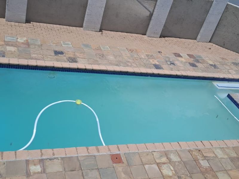 An outdoor swimming pool area featuring stone paving and a surrounding boundary wall.