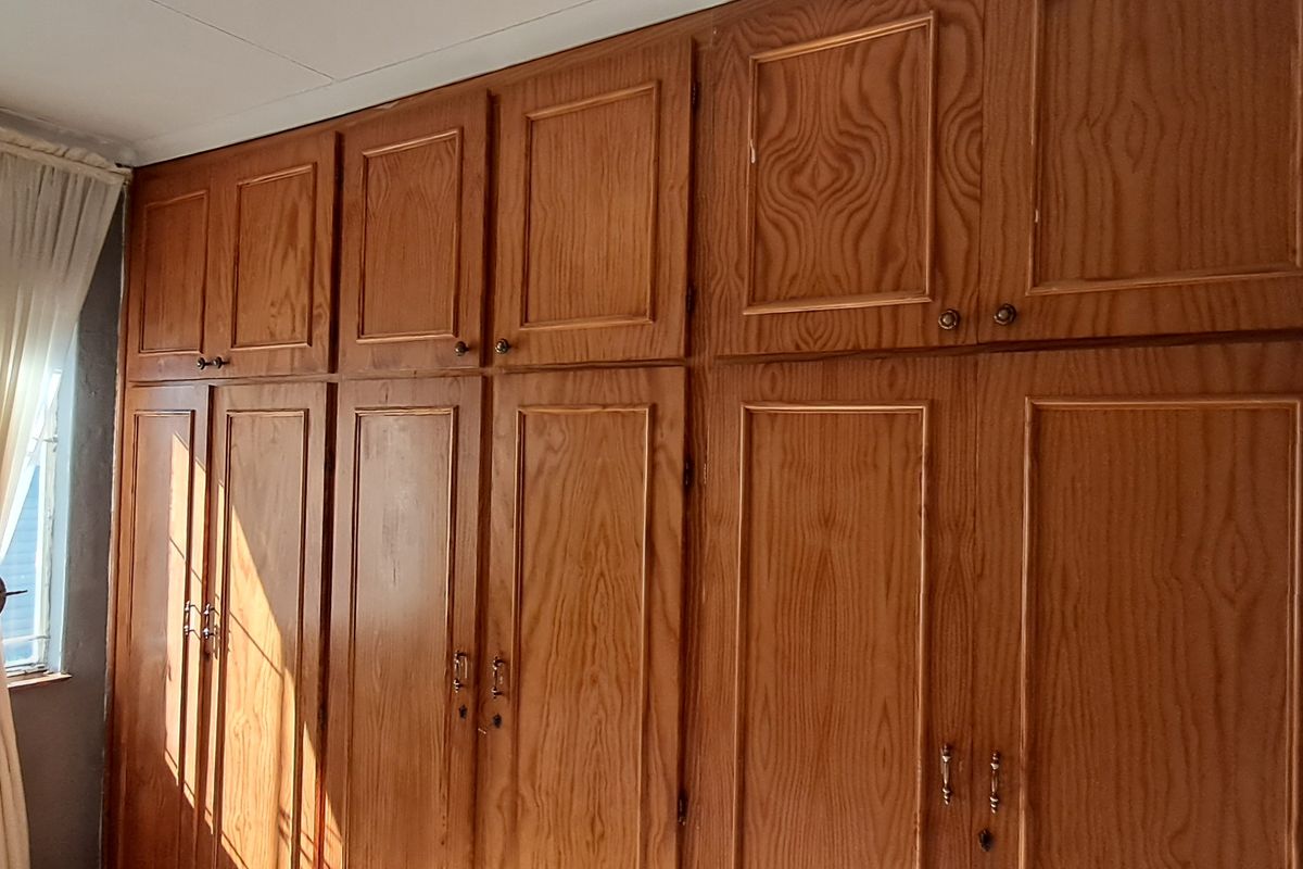 A bedroom featuring extensive floor-to-ceiling wooden built-in cupboards providing ample storage space.
