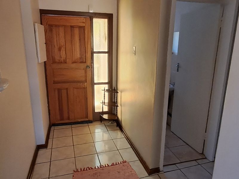 A functional entrance hall featuring tiled flooring, a solid timber front door with a sidelight, and a decorative wall niche.