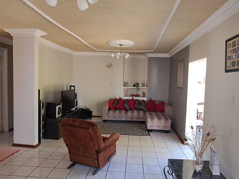 A spacious living room featuring tiled flooring, decorative ceiling coving, and a built-in wall niche, offering a functional layout for relaxation.