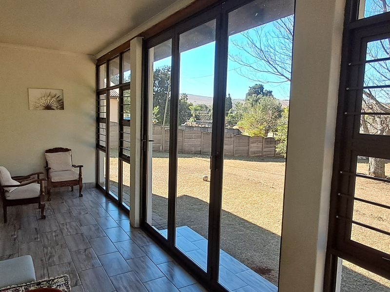 A bright, enclosed patio featuring large glass sliding doors that provide ample natural light and views of the garden.