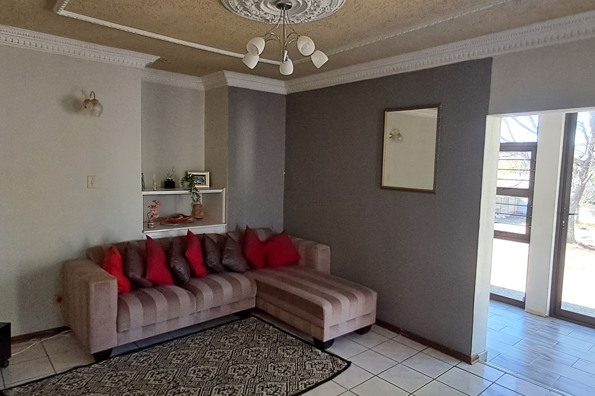 A living room featuring tiled floors, decorative ceiling cornices, a built-in wall niche, and direct access to the garden through a sliding glass door.