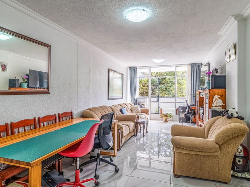 Spacious living area featuring polished tiled flooring, large sliding glass doors providing natural light, and classic ceiling cornice detailing.