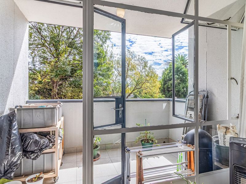 A functional balcony space featuring tiled flooring and large metal-framed glass doors, offering an outdoor area accessible from the main living space.