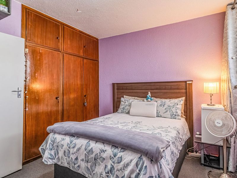 A bedroom featuring built-in wooden wardrobes and carpeted flooring, offering a functional space with potential for modern updates.
