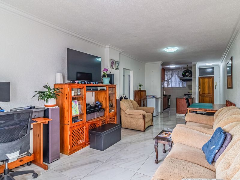 Open plan living and dining area featuring tiled flooring and a connected kitchen space with built-in cabinetry.