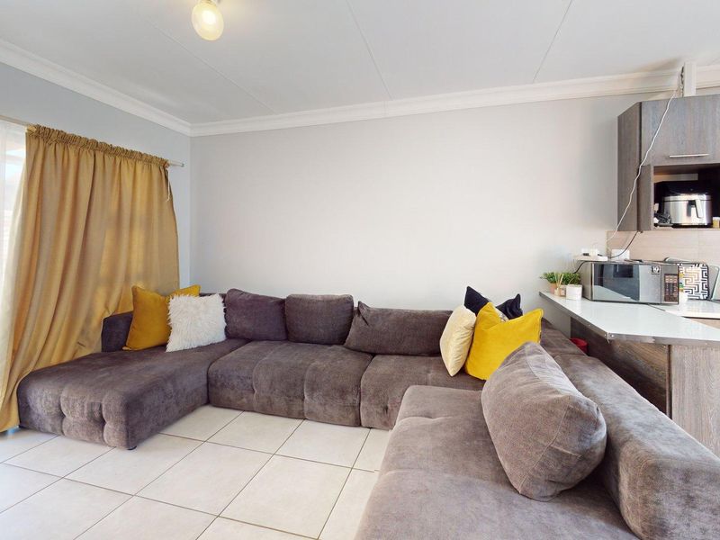 Open-plan living area featuring tiled floors, a modern kitchen with built-in appliances, and a sliding glass door providing access to the outdoor space.
