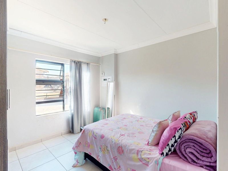 A functional bedroom featuring tiled flooring, a louvered window for ventilation, and a built-in cupboard for storage.