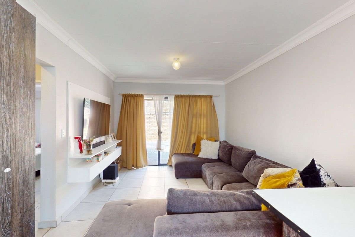 A bright living room featuring tiled flooring, a built-in media console, and a sliding glass door providing access to the outdoor area.