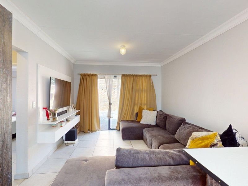 A bright living room featuring tiled flooring, a built-in media console, and a sliding glass door providing access to the outdoor area.