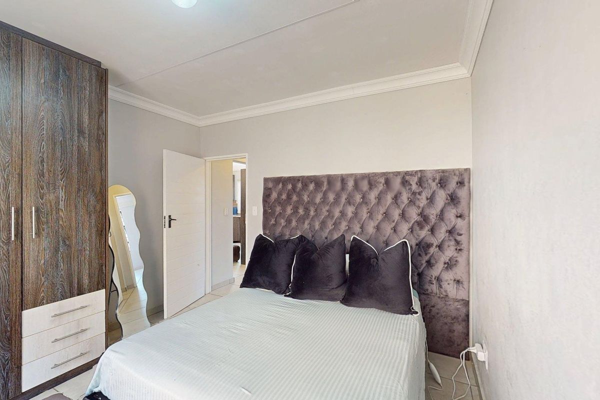 A well-maintained bedroom featuring a built-in wardrobe, decorative coving, and tiled flooring.