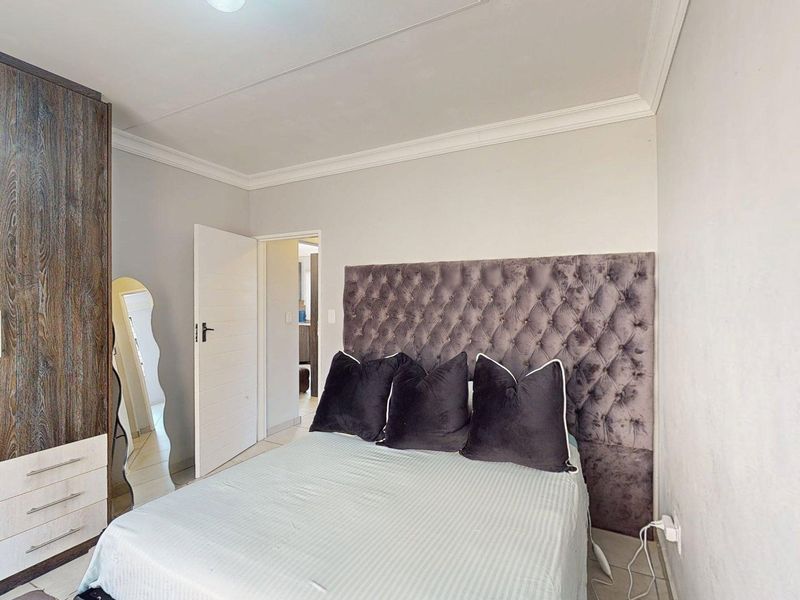 A well-maintained bedroom featuring a built-in wardrobe, decorative coving, and tiled flooring.