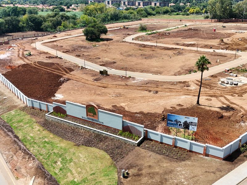 Aerial view of a residential development site featuring perimeter walls, internal paved roads, and established entrance signage.