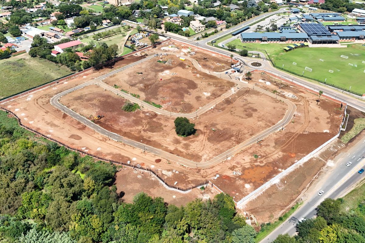 Aerial view of a vacant residential development site featuring established perimeter fencing, internal paved road infrastructure, and street lighting.