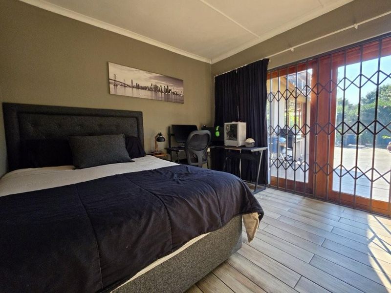 A well-maintained bedroom featuring tiled flooring, cove cornicing, and a sliding glass door with a security gate providing direct access to the outdoor area.