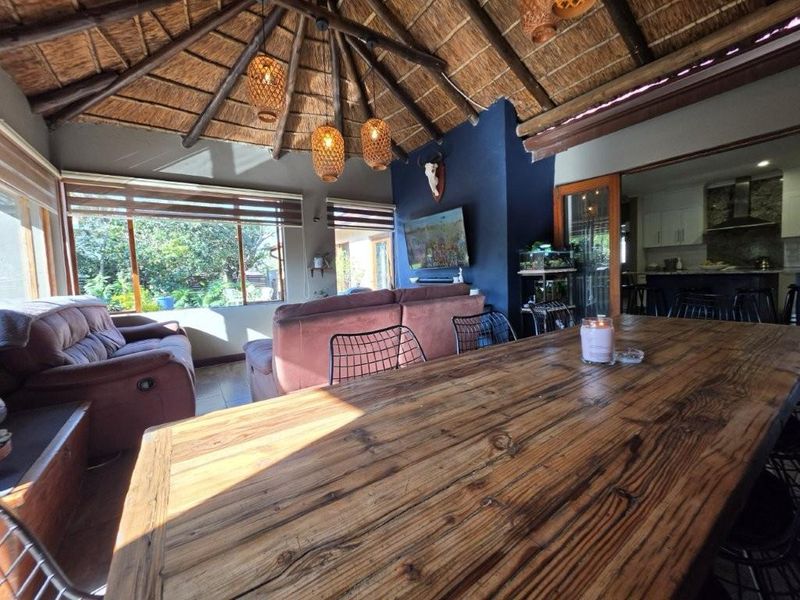 Spacious open-plan living and dining area featuring a distinctive thatched roof with exposed timber rafters and large windows providing ample natural light.