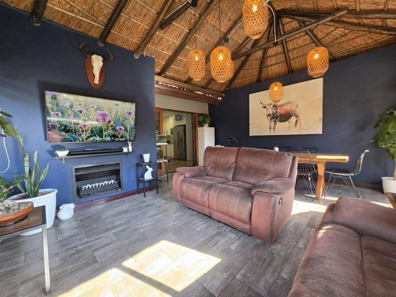 Open-plan living area featuring a distinctive thatched roof with exposed rafters, tiled flooring, and a built-in electric fireplace.