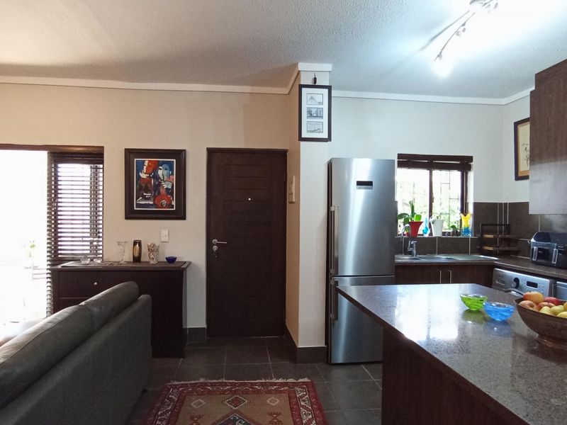 An open-plan living and kitchen area featuring dark wood cabinetry, granite countertops, tiled flooring, and direct access to an outdoor space.