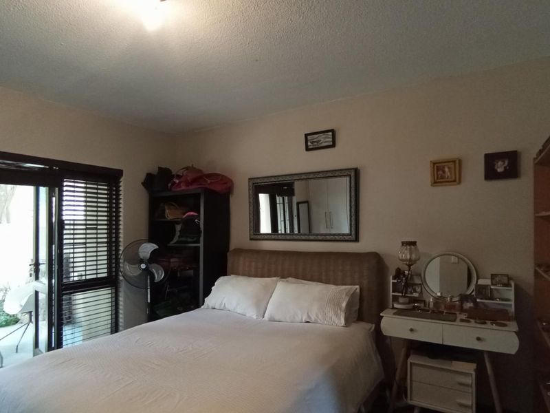 A bedroom featuring a sliding glass door with venetian blinds, providing access to an outdoor area.