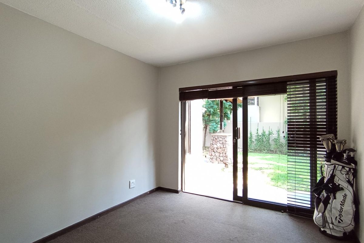A bright, empty bedroom featuring neutral walls, carpeted flooring, and a sliding glass door that provides direct access to the garden area.