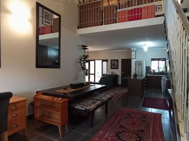 Open-plan living and kitchen area featuring a staircase leading to a mezzanine level, tiled flooring, and integrated kitchen cabinetry.