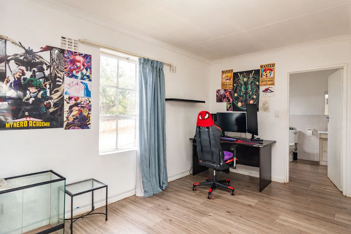 A bedroom featuring laminate flooring, a window, and an attached en-suite bathroom.