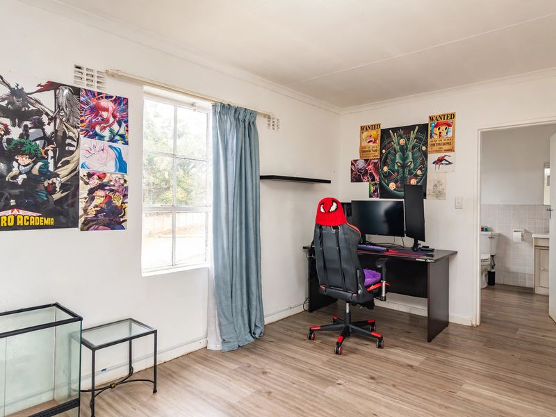 A bedroom featuring laminate flooring, a window, and an attached en-suite bathroom.