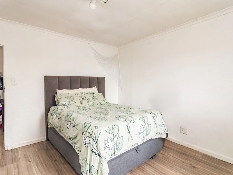 A simple bedroom featuring laminate flooring and white walls, offering a blank canvas for potential interior updates and modernization.