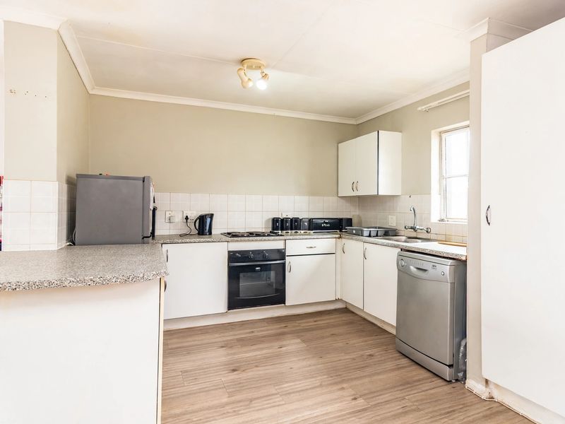 A functional kitchen featuring white cabinetry, laminate countertops, a built-in oven, and a tiled backsplash, with wood-look laminate flooring throughout.