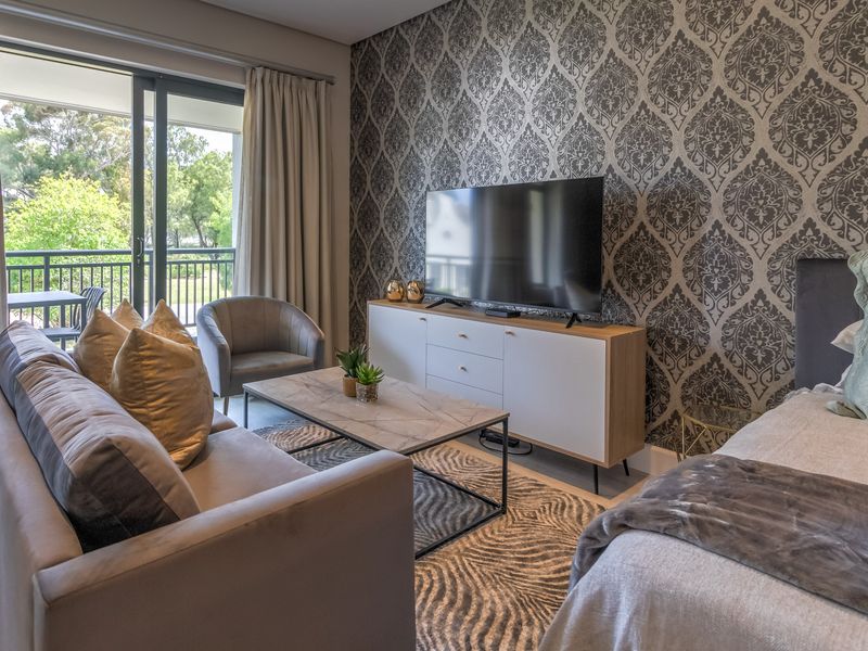 A well-appointed bedroom featuring decorative patterned wallpaper, a sliding glass door leading to a private balcony, and neutral flooring.
