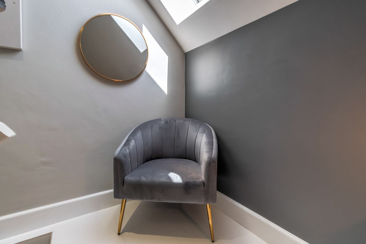 A cozy corner featuring a skylight that provides natural illumination, highlighting the contrasting grey wall finishes.