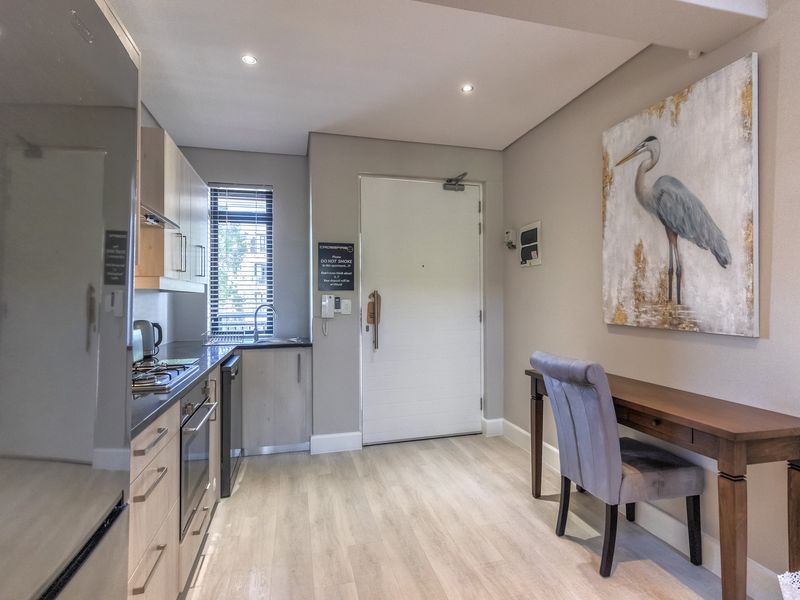 Modern kitchen featuring light wood cabinetry, integrated appliances, gas hob, and sleek laminate flooring, creating a functional and contemporary cooking space.