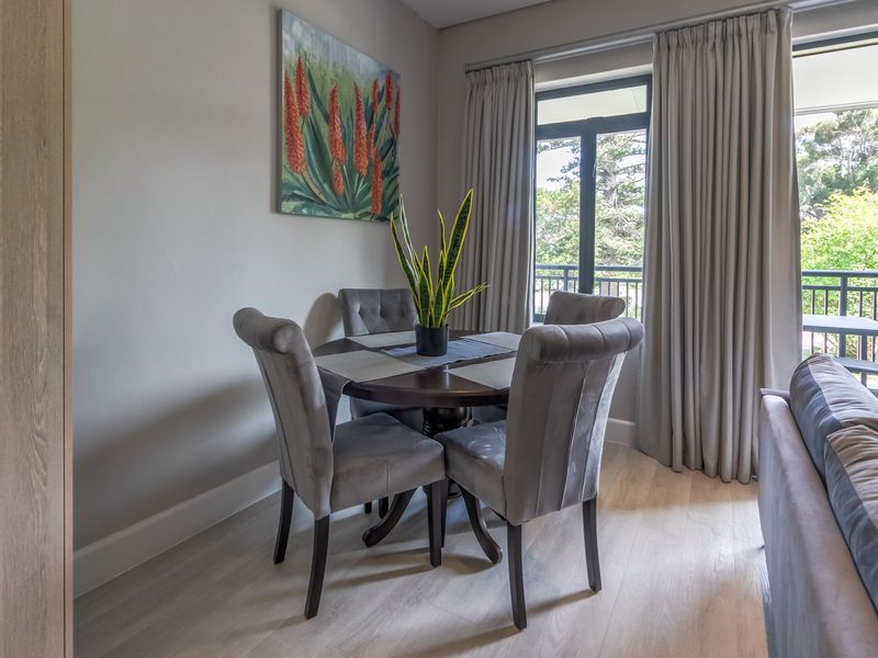 A bright dining area featuring light-toned laminate flooring and direct access to an outdoor balcony through a sliding glass door.