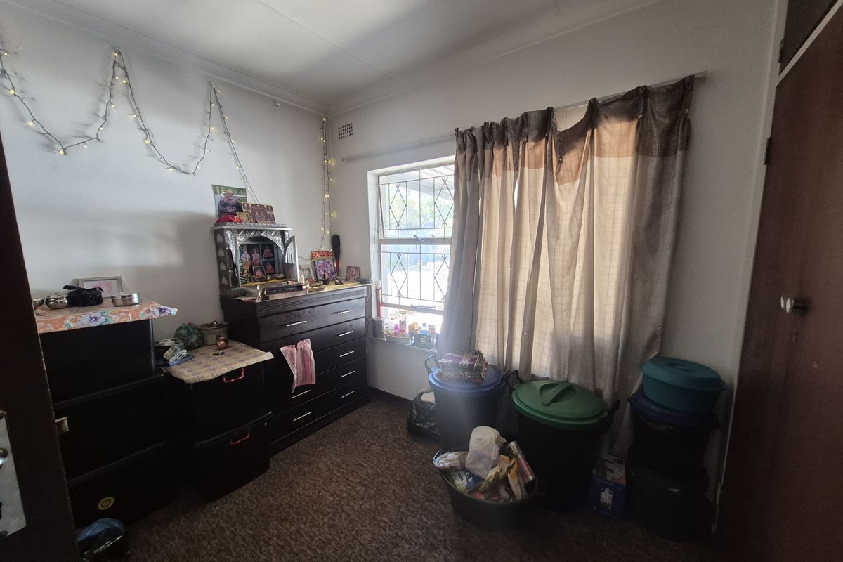 A bedroom featuring carpeted flooring, a built-in cupboard, and a window fitted with a security gate.