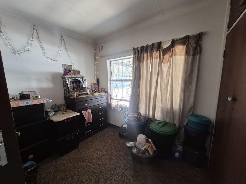 A bedroom featuring carpeted flooring, a built-in cupboard, and a window fitted with a security gate.