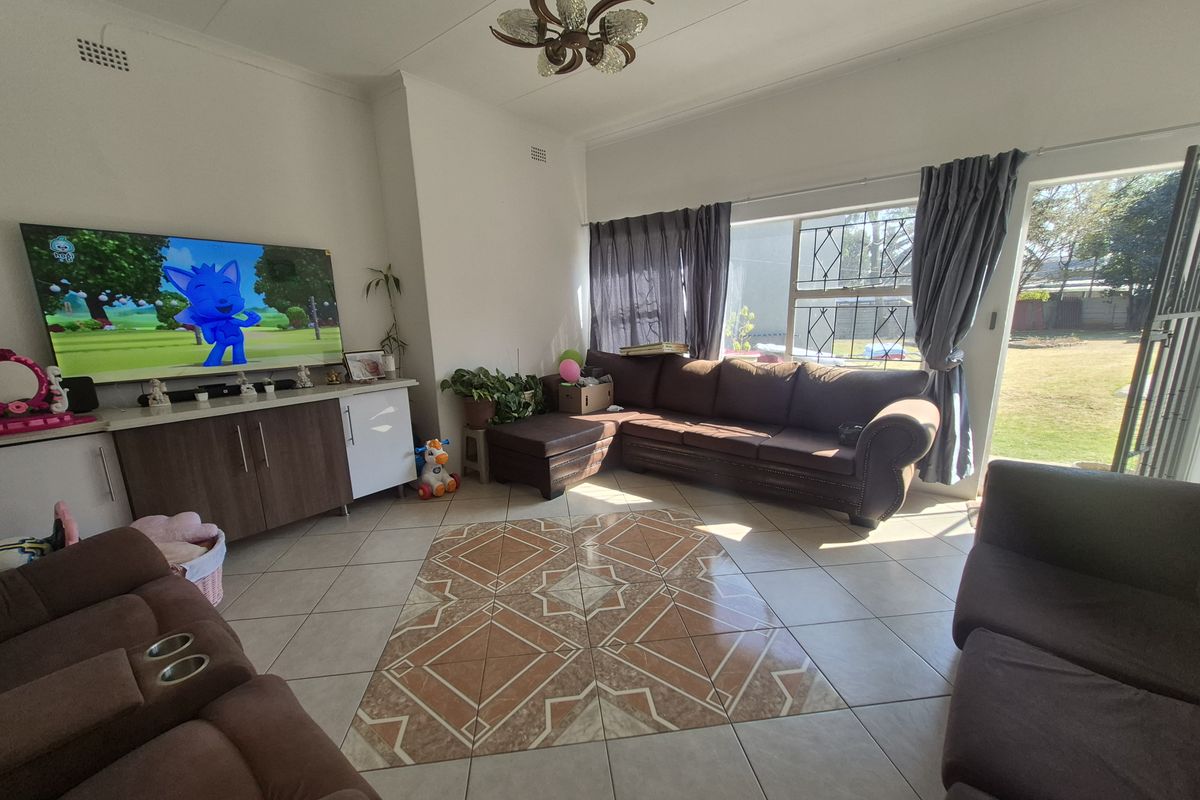 Spacious living room featuring tiled flooring with a decorative inlay, built-in cabinetry, and direct access to the garden through a sliding door.