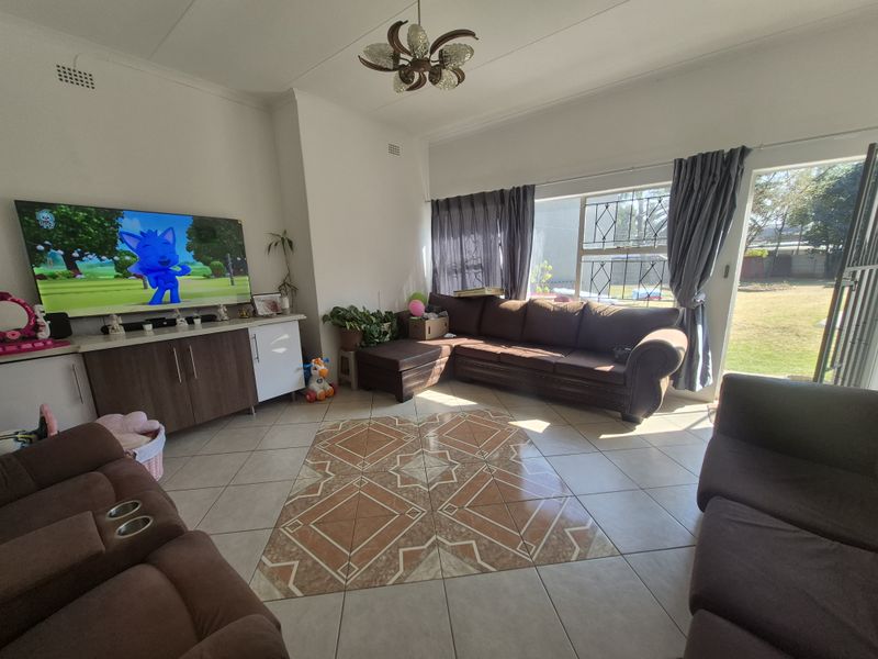 Spacious living room featuring tiled flooring with a decorative inlay, built-in cabinetry, and direct access to the garden through a sliding door.