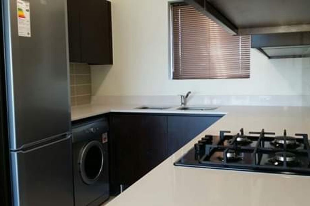 Modern kitchen featuring dark cabinetry, stone countertops, a gas hob, and a tiled splashback with a functional layout.